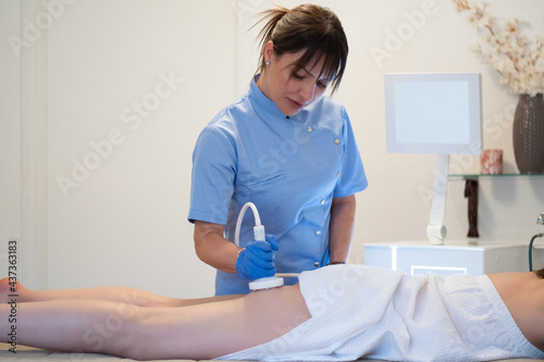 The therapist in the salon massages the client's thighs with the ultra sound. Ultrasound Fat Reduction in fatty areas. Dermo massage with cosmetic equipment that improves appearance of cellulite photo