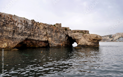 Photo of sea caves and a rock arch made by a boat around the coast of Malta, Europe.