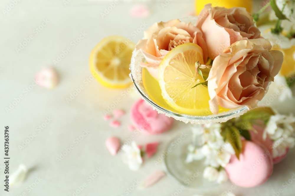 Glass of cocktail, ingredients and flowers on white textured table Glass of cocktail, ingredients and flowers on white textured table
