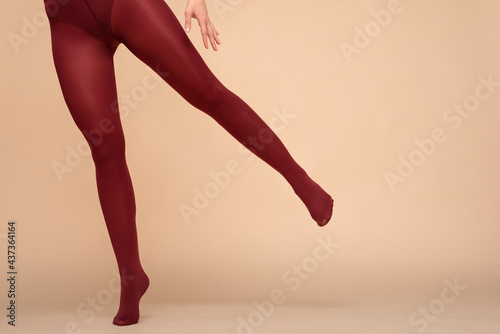 Female legs in the red stockings on a light background in the fitting room.
