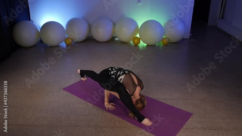 Eka Pada Koundinyasana. Hurdler Pose. Flying Splits. A flexible middle-aged blonde doing yoga at a fitness club. She does asana yoga on a mat. photo