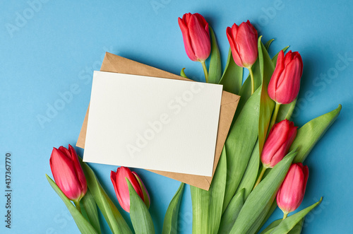Greeting card mockup with copy space, fresh red tulips on blue paper background