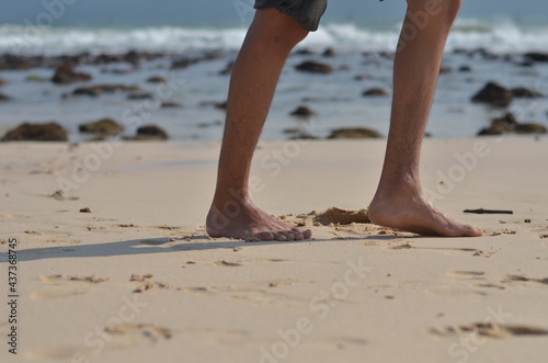 male foots or feet running gesture in the beach with blurred sea background