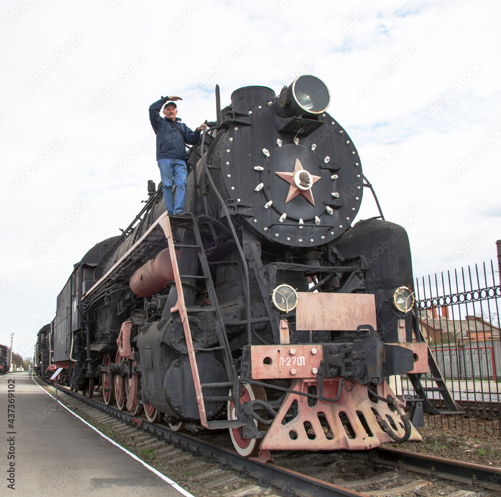 Obraz premium The machinist of a steam locomotive looks afar