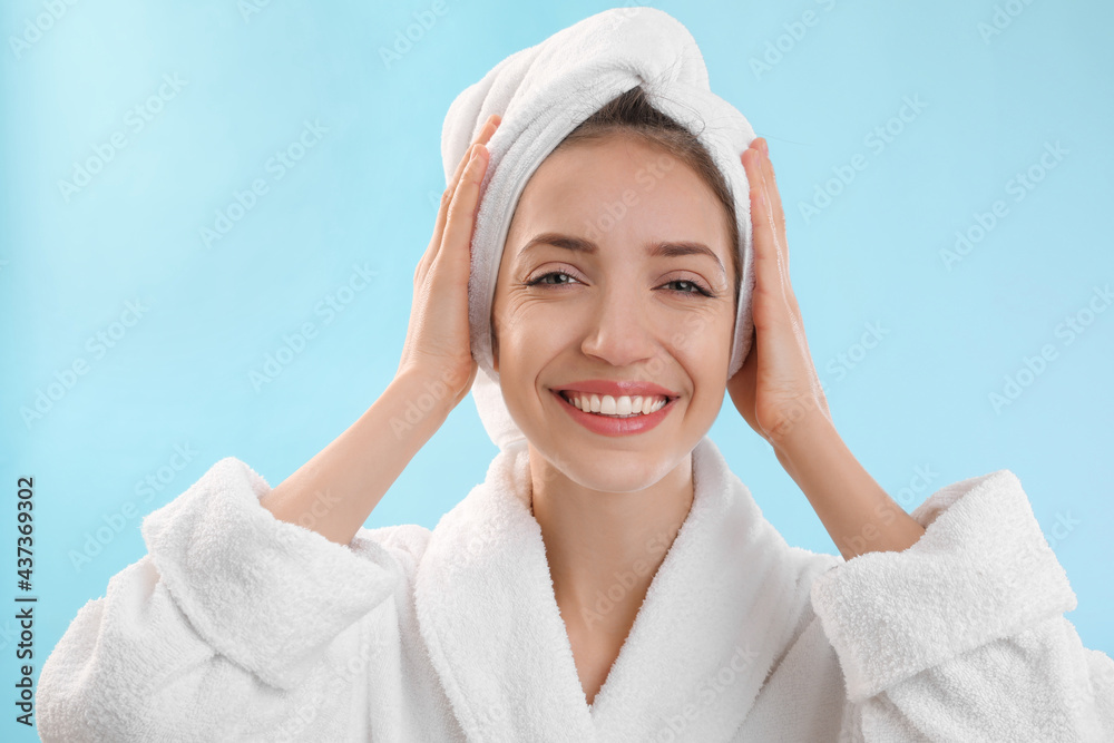 Beautiful young woman with hair wrapped in towel after washing on light blue background Beautiful young woman with hair wrapped in towel after washing on light blue background
