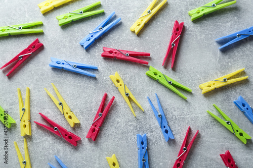 Colorful plastic clothespins on grey table, flat lay