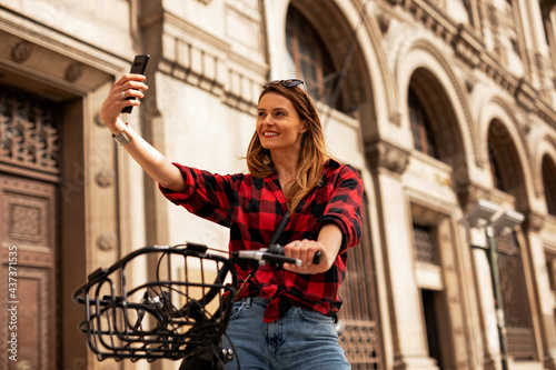 Young lady with bicycle on the street. Beautiful girl taking selfie photo