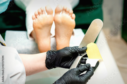 The pedicure master putting on new sandpaper on the metal handle before the procedure of cleaning the foot and heel in a nail salon