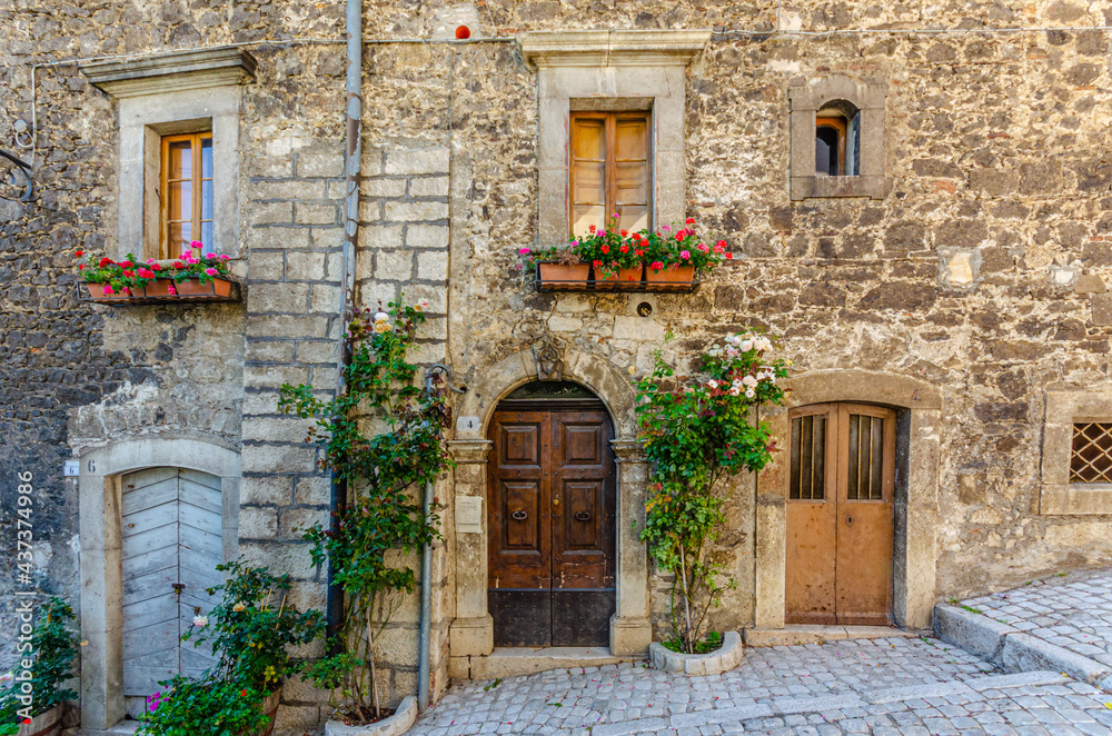 Pescocostanzo, Italy. August 24th, 2012. Facades of historic buildings with entrance and windows decorated with plants and flower pots of different colors.