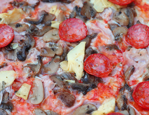 detail of pizza called capricciosa with mushrooms artichokes spicy salami and tomato mozzarella in an Italian pizzeria photo