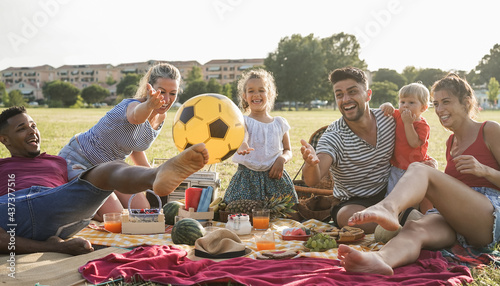 Happy multiracial families doing picnic outdoor in city park during summer vacation - Main focus on african man face