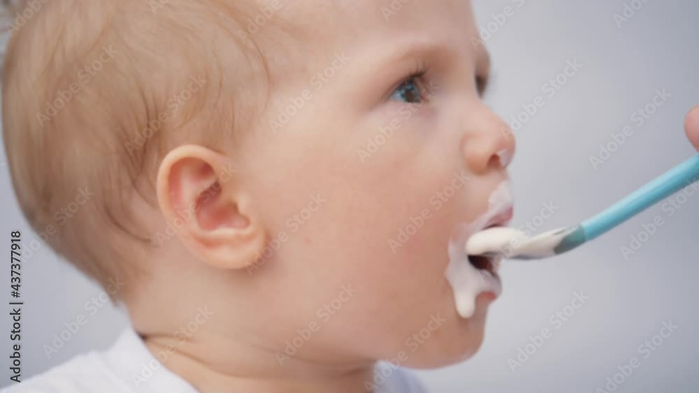 mother feeds her little son from a spoon with porridge. The kid is eating breakfast from a spoon. loving mother takes care of the child, spoon feeds porridge. mother feeds her little son from a spoon with porridge. The kid is eating breakfast from a spoon. loving mother takes care of the child, spoon feeds porridge.