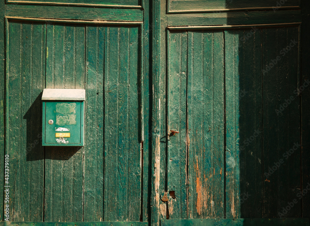 Green mailbox on a green wood door
