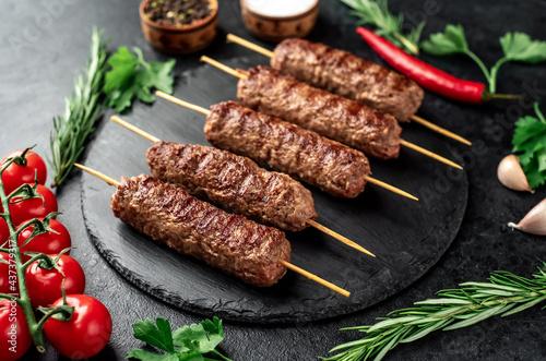 grilled Lula kebab on skewers with spices on a stone background