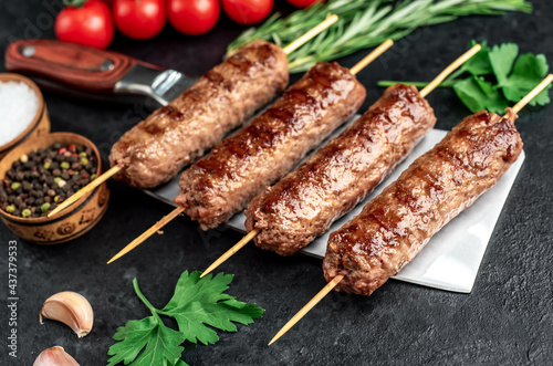 grilled Lula kebab on skewers with spices on the knife on a stone background