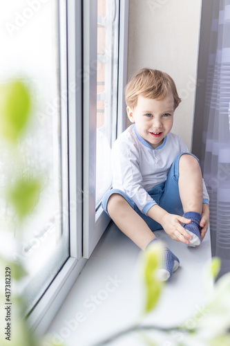 a child boy looks out of the window sitting on the window sill of the house