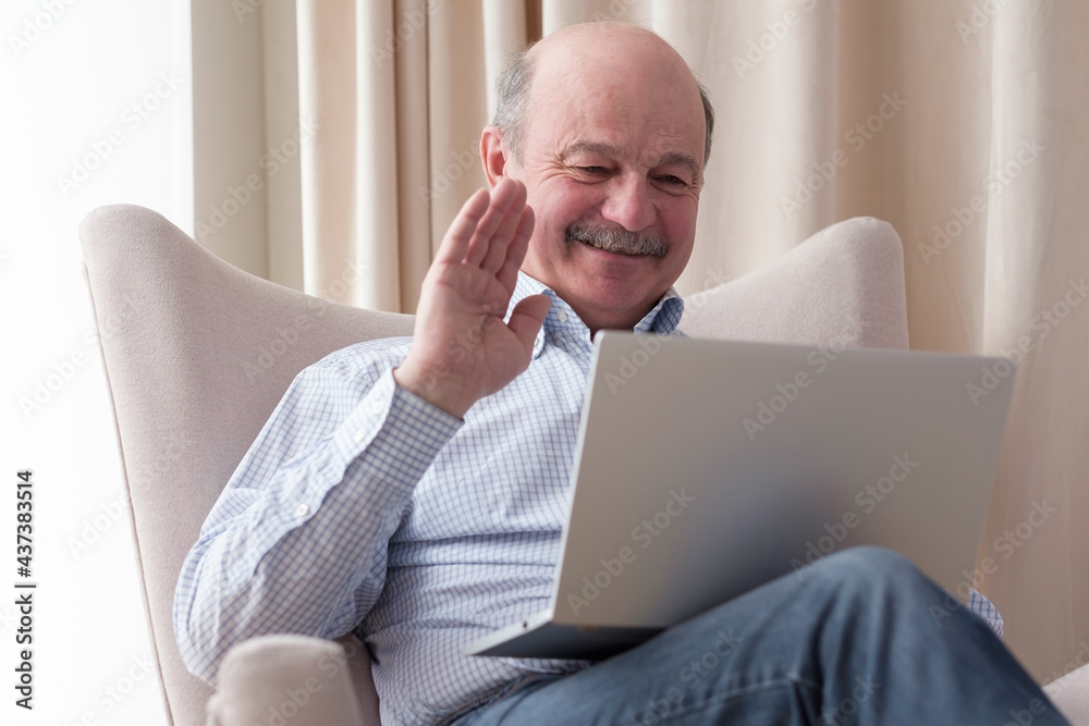 Man sitting in the living room and having videochat on the laptop computer