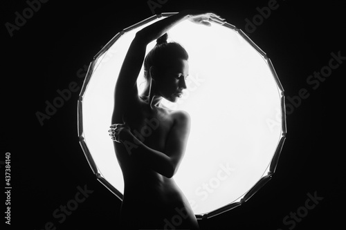 The silhouette of a young, slender, in the light of softbox.