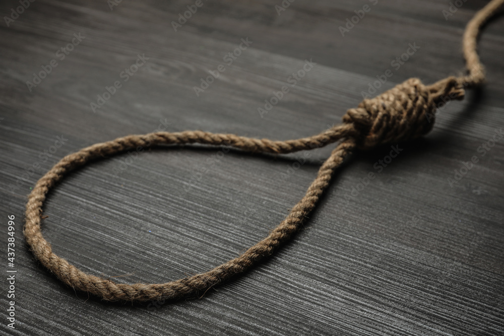 Rope noose on black wooden table, closeup