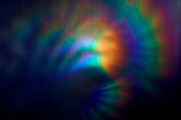 Blurred Bright multicolored glare on dark rough textured cardboard. Soft rainbow light. Abstract colorful background. Unusual light effect.