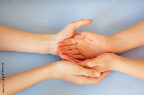 Children hold each other's hands. The hand lies in the hand close-up. On a blue background. Place for your text.