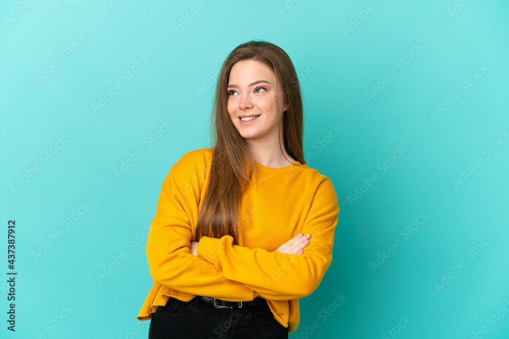 Obraz premium Teenager girl over isolated blue background looking up while smiling