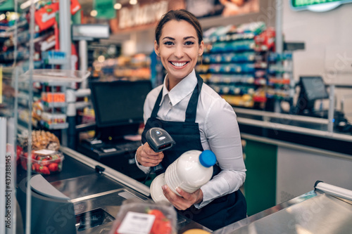 Portrait of beautiful smiling cashier working at a grocery store. photo