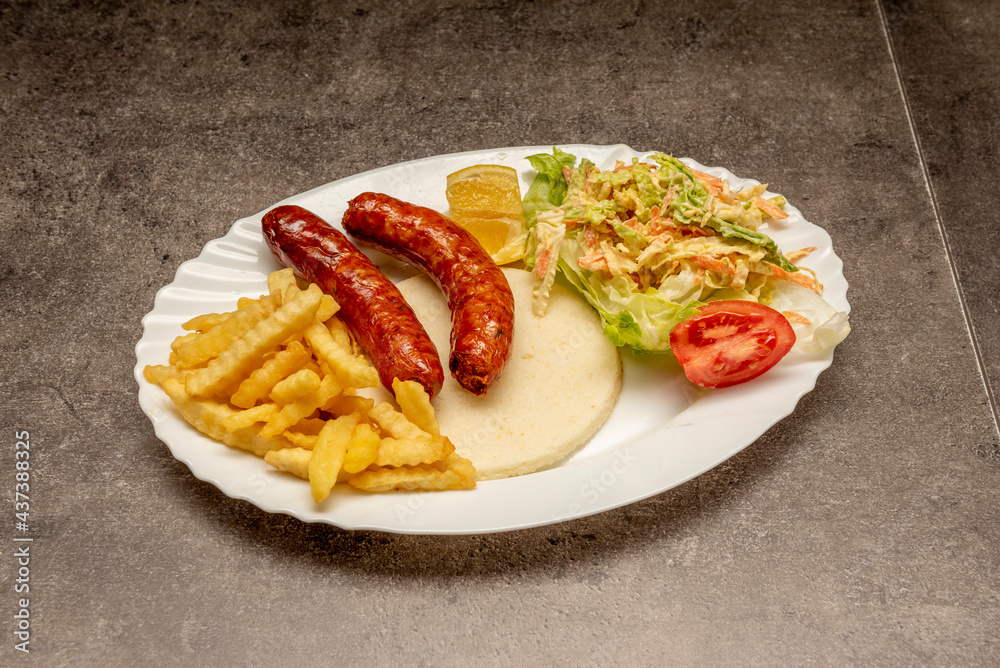 Venezuelan arepa breakfast with fried sausages, coleslaw and chips Venezuelan arepa breakfast with fried sausages, coleslaw and chips