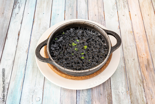 metal casserole containing a portion of black seafood paella to serve as tapas in a Spanish restaurant