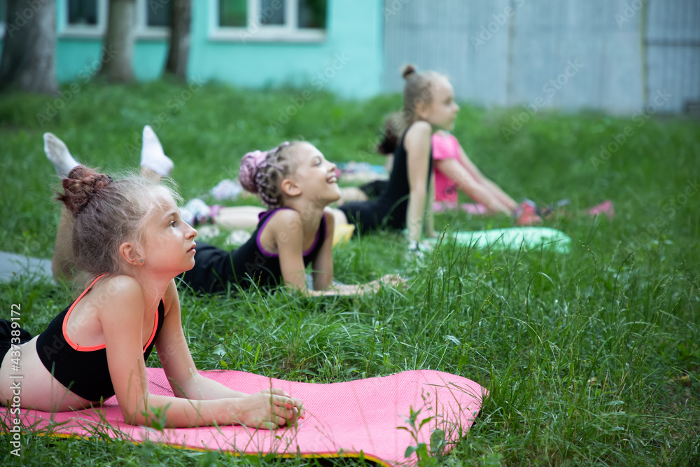 Naklejka premium Girls gymnasts listening to somebody on training outdoors in summer