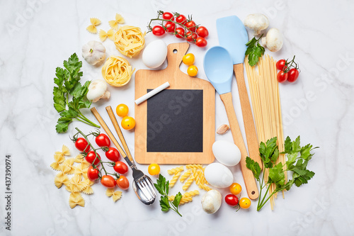 Pasta cooking background with chalkboard, tomatoes, herbs, mushrooms, eggs, top view. Italian cuisine concept