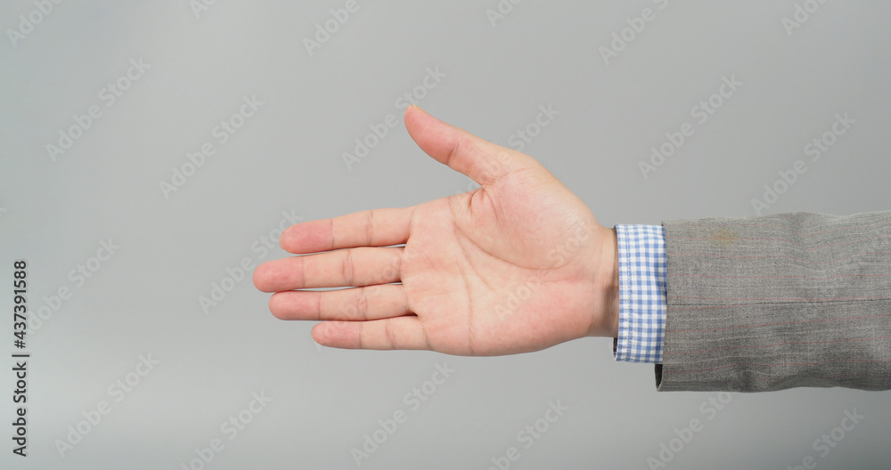 Handshake gesture in grey suit on grey background. Businessman topic.close up photo and studio shooting. Handshake gesture in grey suit on grey background. Businessman topic.close up photo and studio shooting.