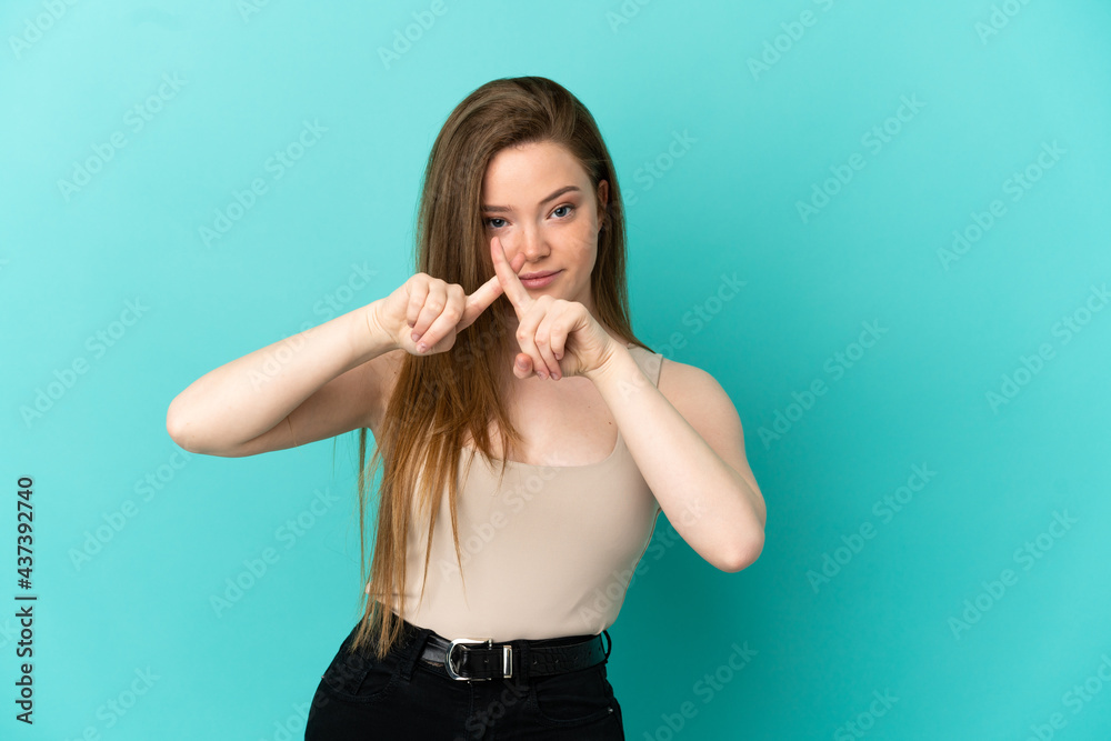 Teenager girl over isolated blue background making stop gesture with her hand to stop an act
