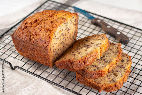 Sliced loaf of banana bread cupcake with poppy seeds on cooling wrack