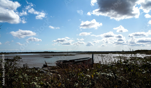 Empty estuary deserted in spring sun with abandoned boat on shore