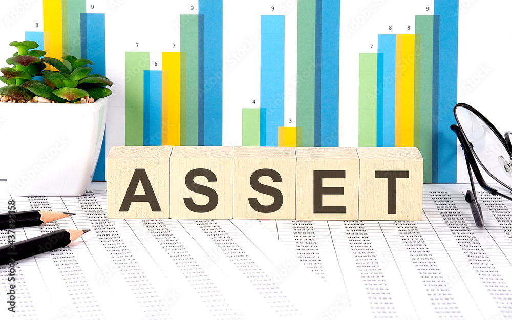 ASSET word written on wood block with chart, glasses and pencils ASSET word written on wood block with chart, glasses and pencils