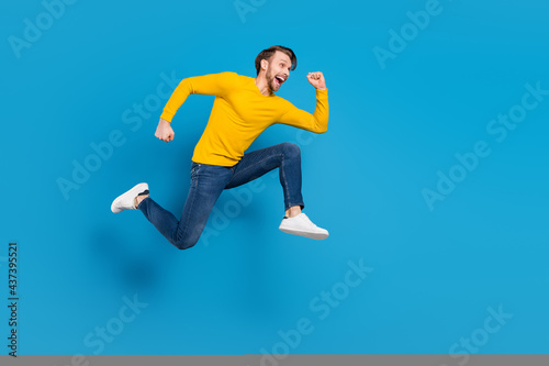 Full length side profile body size of young guy jumping high running on sale isolated vivid blue color background