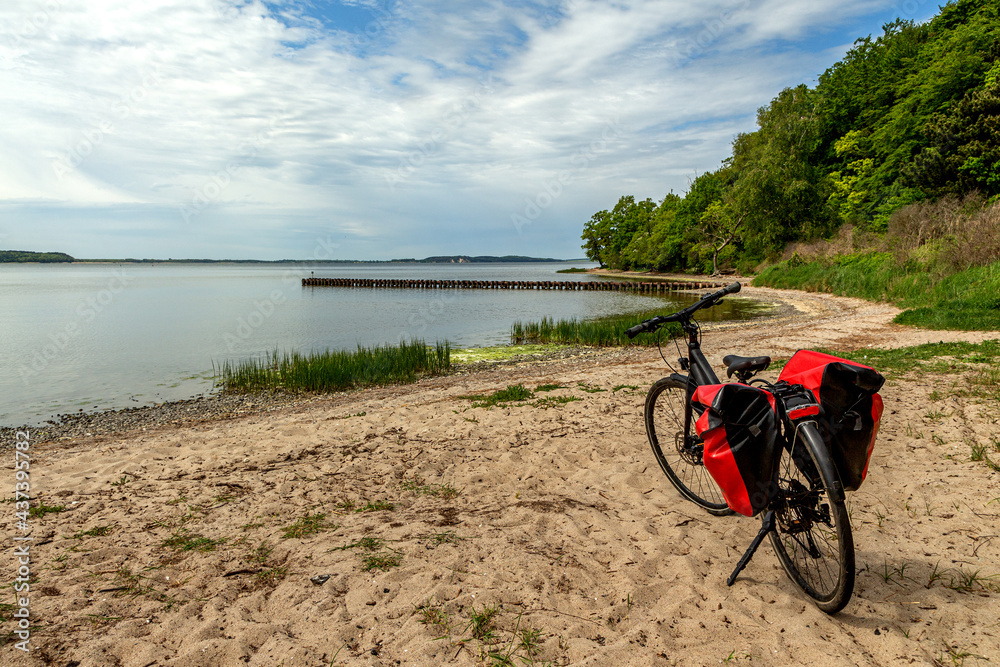 Fototapeta premium Fahrrad am strand, am see mit Sand und Wolken und Wald, Fahrradtour, Fahrradwanderung mit Fahrrad und Fahrradtaschen
