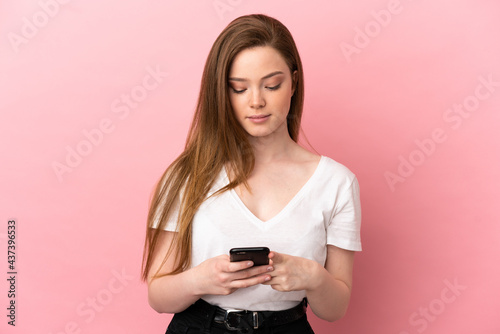 Teenager girl over isolated pink background using mobile phone