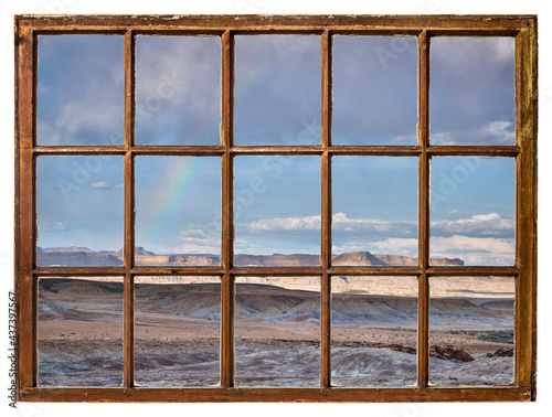 rock desert landscape with a rainbow as seen from a vintage cabin window
