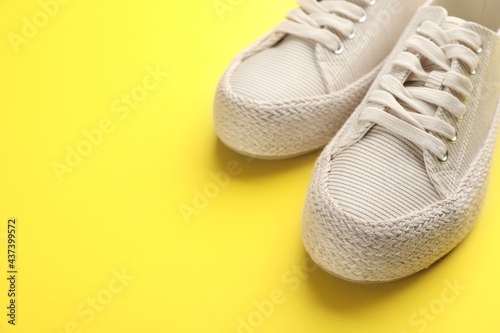 Pair of stylish comfortable shoes on yellow background,closeup. Space for text