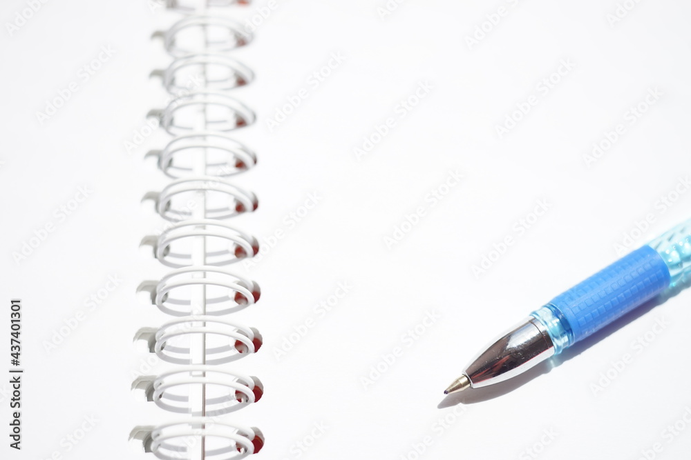Blue ball pen on a sunny white notebook paper Blue ball pen on a sunny white notebook paper