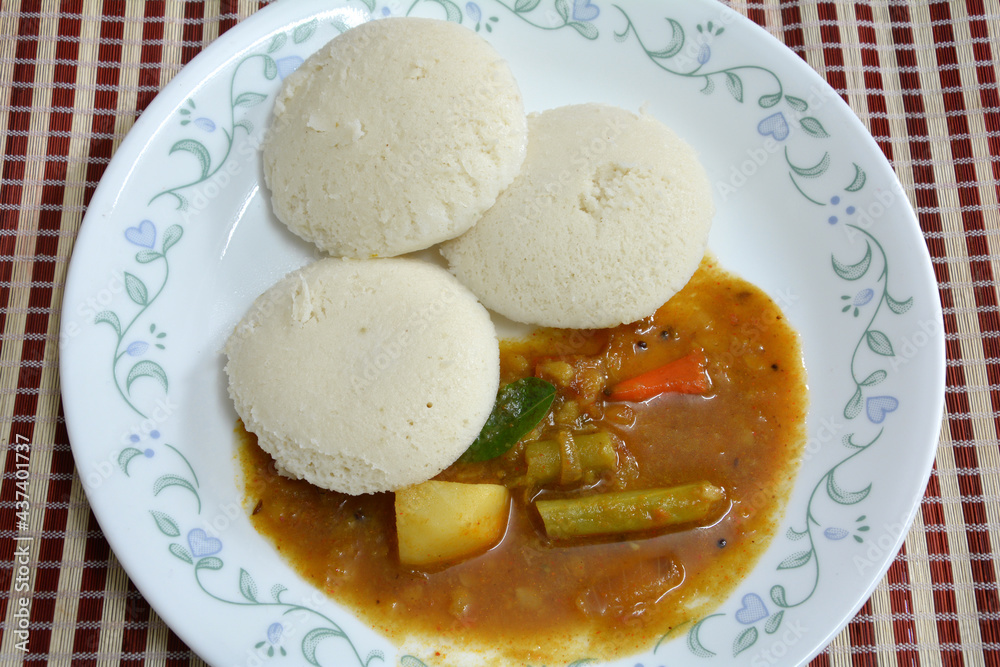Wholesome South Indian breakfast. Three idlis and sambar on porcelain plate, top down view. Popular food combination in Kerala and Tamil Nadu. Wholesome South Indian breakfast. Three idlis and sambar on porcelain plate, top down view. Popular food combination in Kerala and Tamil Nadu.