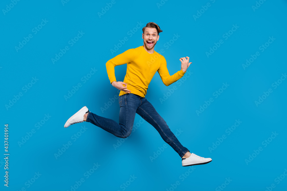 Fototapeta premium Full length body size of young guy smiling jumping up pretending playing guitar isolated vivid blue color background
