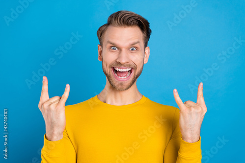 Photo of young excited guy happy positive smile show rock sign heavy brutal isolated over blue color background