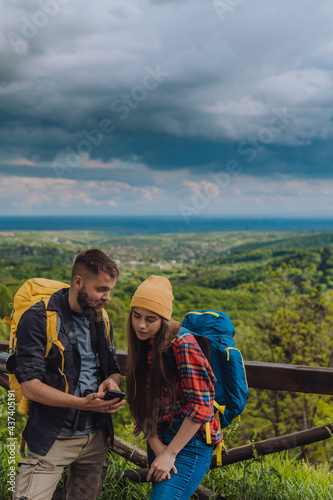 A couple of hikers using smartphone for orientation while spending time in nature