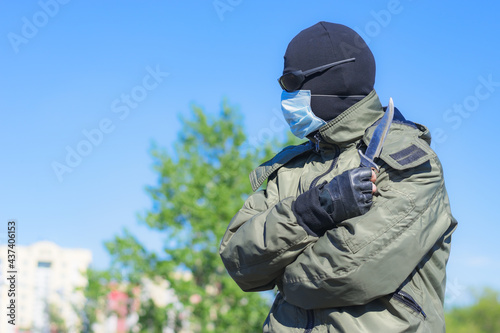 Modern dangerous and armed criminal in balaclava and medical mask among city streets © Николай Чекалин