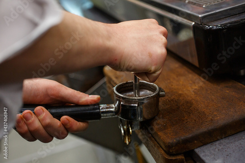 Barista mentre pressa il caffè appena messo nel braccio di una macchina da caffè professionale