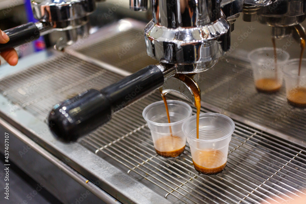 Caffè mentre scende da una macchina da caffè professionale in due bicchierini di plastica monouso trasparente Caffè mentre scende da una macchina da caffè professionale in due bicchierini di plastica monouso trasparente