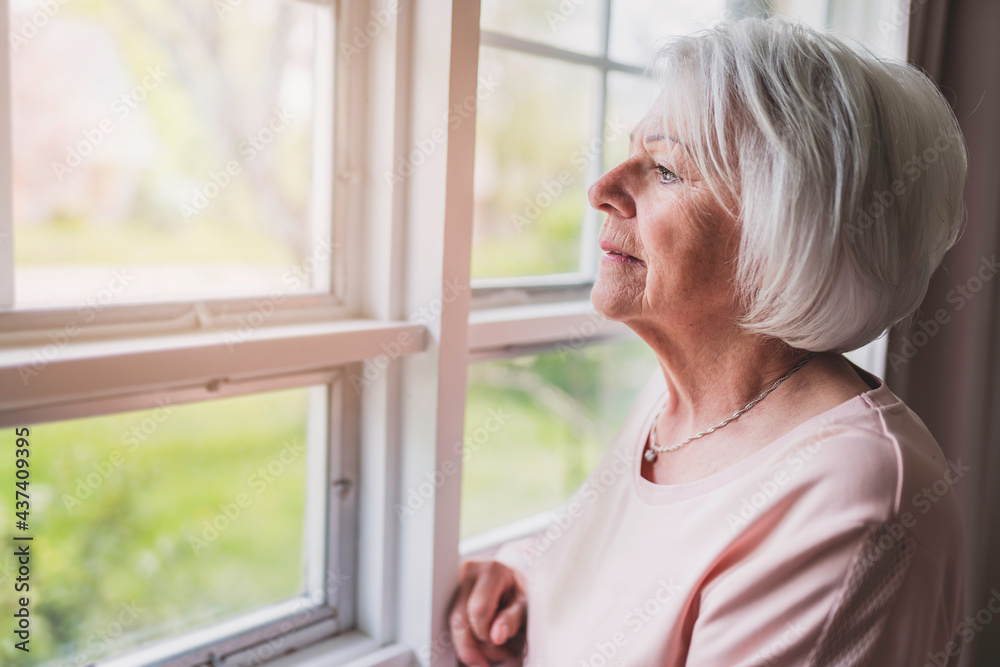 Middle aged female in front of curtains close to a window feel lonely Middle aged female in front of curtains close to a window feel lonely